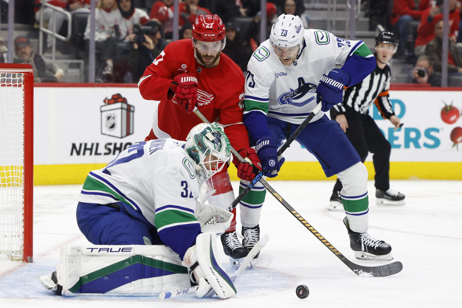 Dec 1, 2024; Detroit, Michigan, USA; Vancouver Canucks goaltender Kevin Lankinen (32) makes a save in front of defenseman Vincent Desharnais (73) and Detroit Red Wings center Michael Rasmussen (27) in the second period at Little Caesars Arena. Mandatory Credit: Rick Osentoski-Imagn Images
