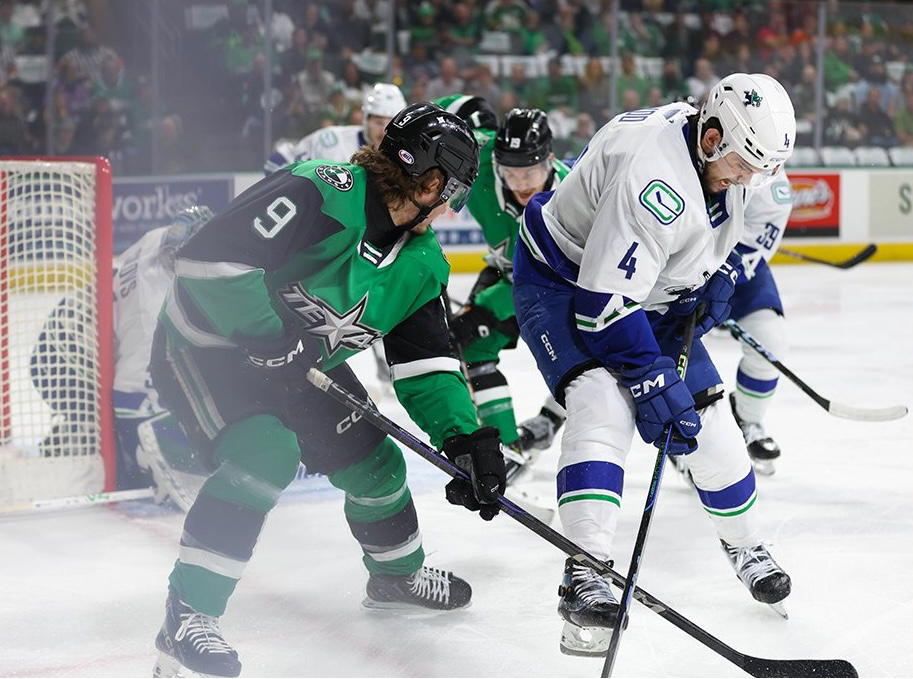 Abbotsford Canucks defenceman Jett Woo (4) battles with Texas Stars forward Justin Hryckowian (9). (Photo Credit: @TexasStars/X)&nbsp;