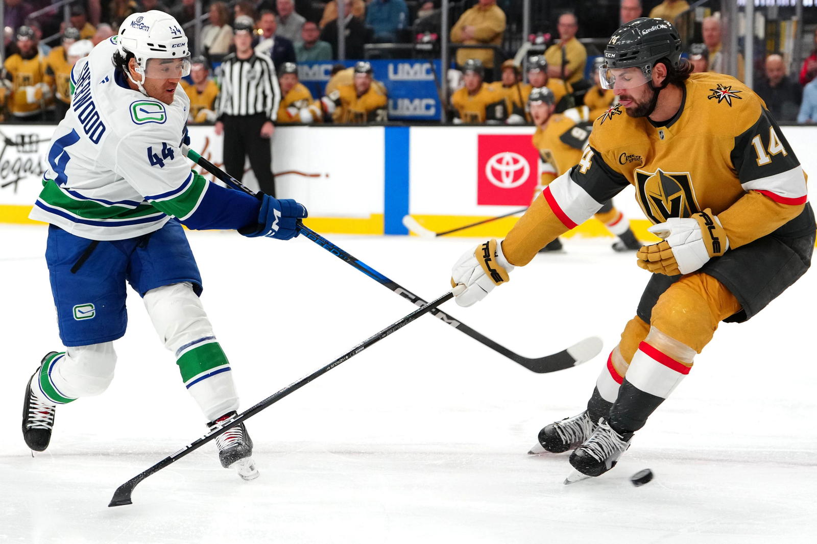 Feb 22, 2025; Las Vegas, Nevada, USA; Vancouver Canucks left wing Kiefer Sherwood (44) shoots against the stick of Vegas Golden Knights defenseman Nicolas Hague (14) during the first period at T-Mobile Arena. Mandatory Credit: Stephen R. Sylvanie-Imagn Images