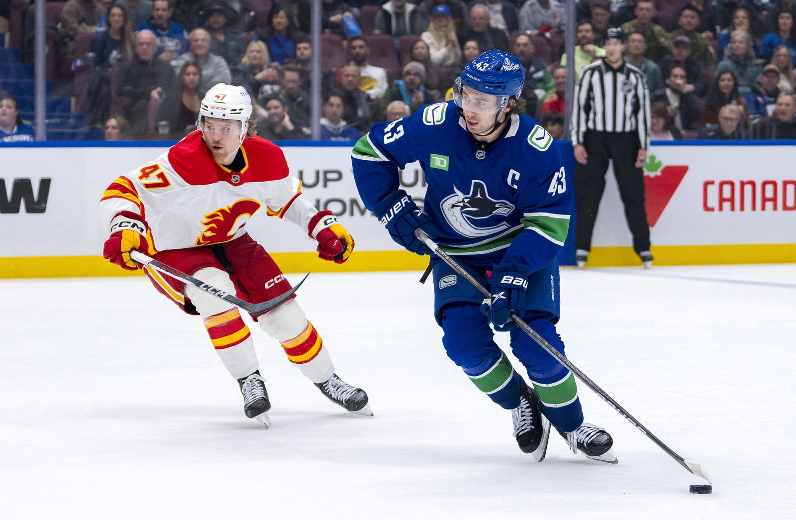 Nov 12, 2024; Vancouver, British Columbia, CAN; Vancouver Canucks defenseman Quinn Hughes (43) skates with the puck against Calgary Flames forward Connor Zary (47) during the second period at Rogers Arena. Mandatory Credit: Bob Frid-Imagn Images