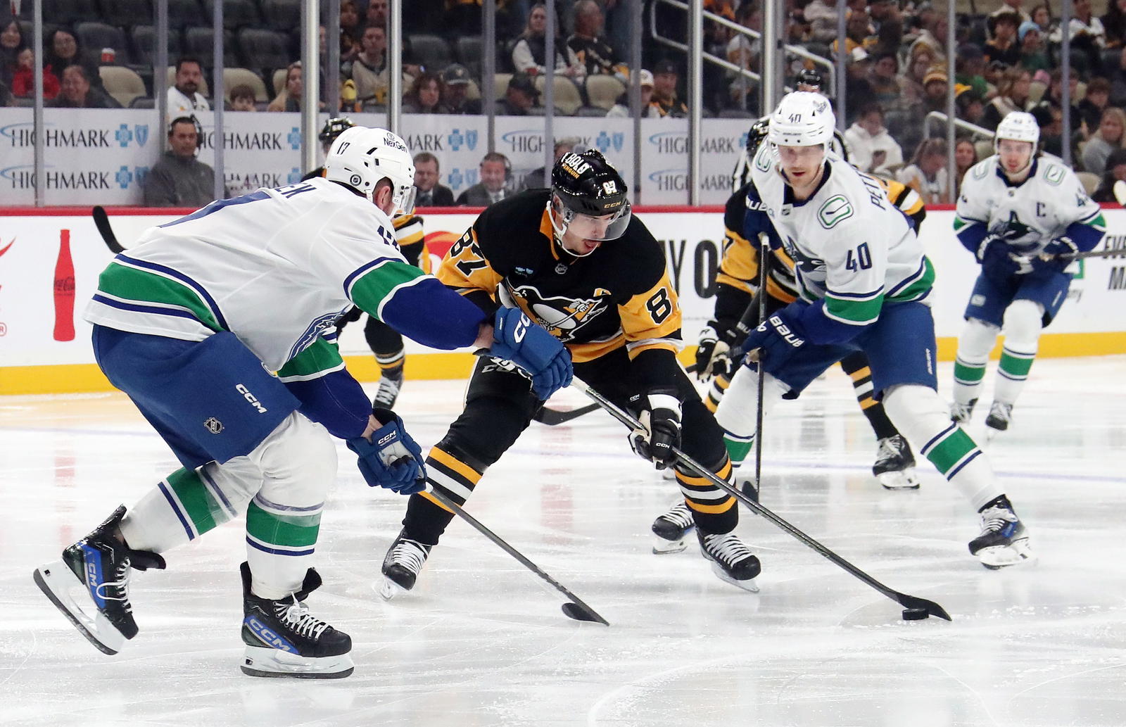 Nov 27, 2024; Pittsburgh, Pennsylvania, USA; Pittsburgh Penguins center Sidney Crosby (87) moves the puck between Vancouver Canucks defenseman Filip Hronek (left) and center Elias Pettersson (40) during the third period at PPG Paints Arena. Mandatory Credit: Charles LeClaire-Imagn Images