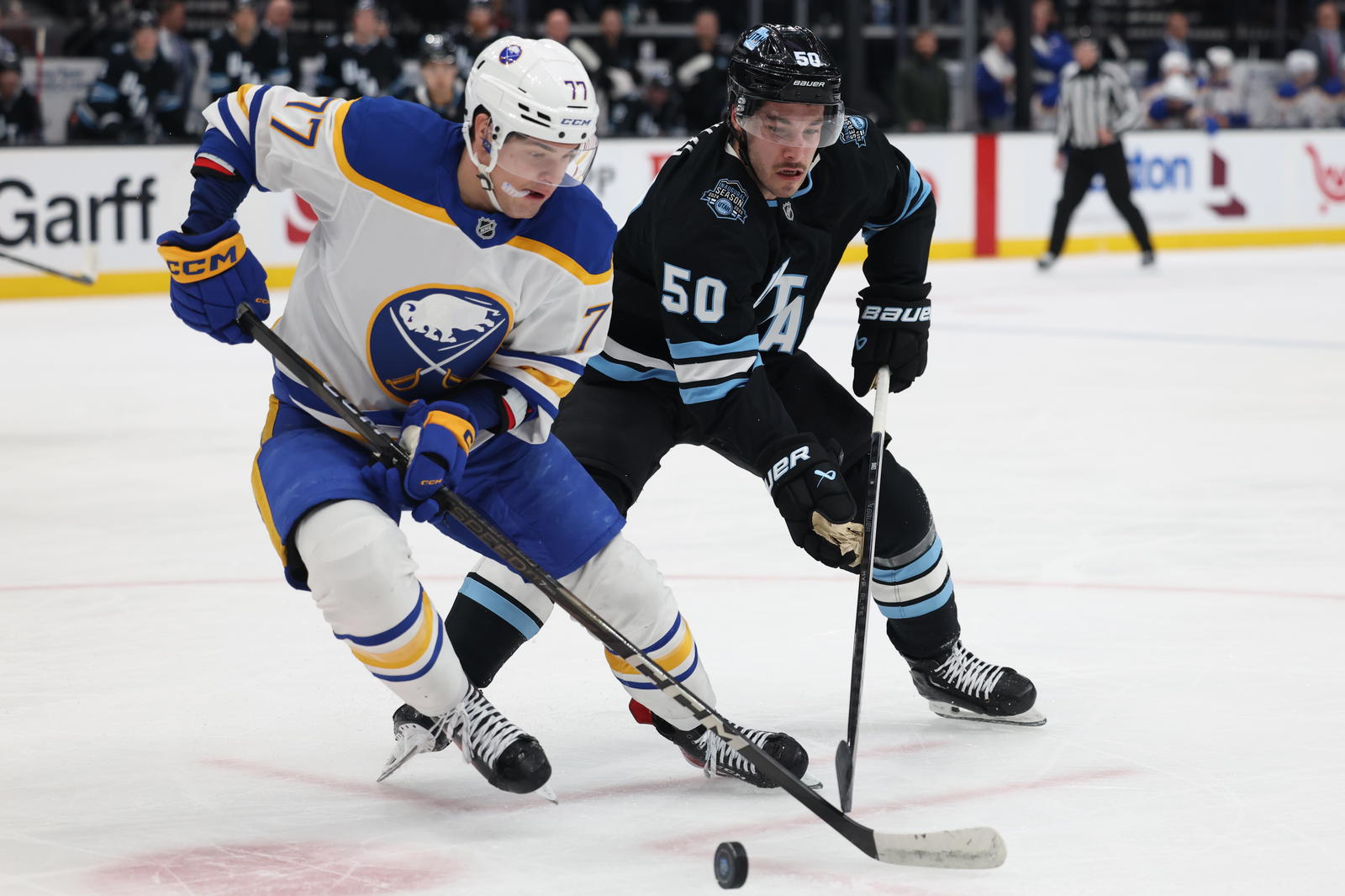 Mar 20, 2025; Salt Lake City, Utah, USA; Buffalo Sabres right wing JJ Peterka (77) and Utah Hockey Club defenseman Sean Durzi (50) battle for the puck during the first period at Delta Center. Mandatory Credit: Rob Gray-Imagn Images