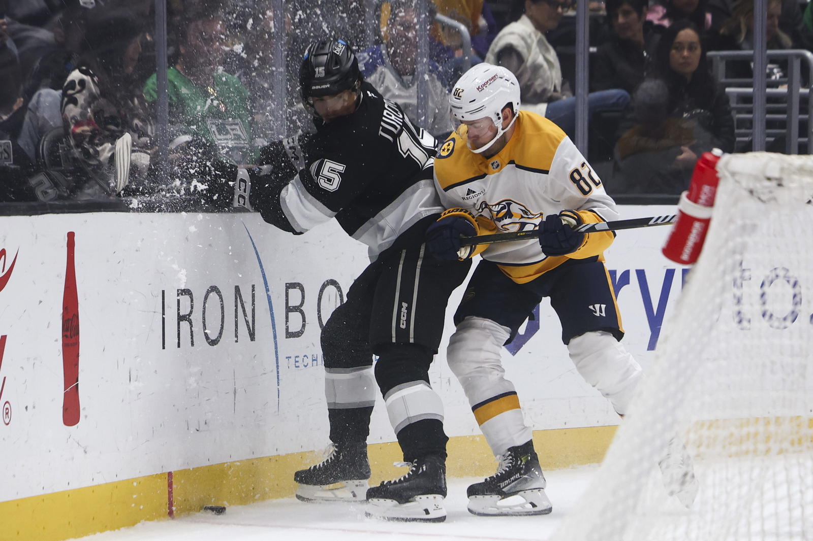 ar 15, 2025; Los Angeles, California, USA; Nashville Predators defenseman Jordan Oesterle (82) checks Los Angeles Kings center Alex Turcotte (15) into the boards during the second period of a hockey game at Crypto.com Arena. Mandatory Credit: Jessica Alcheh-Imagn Images