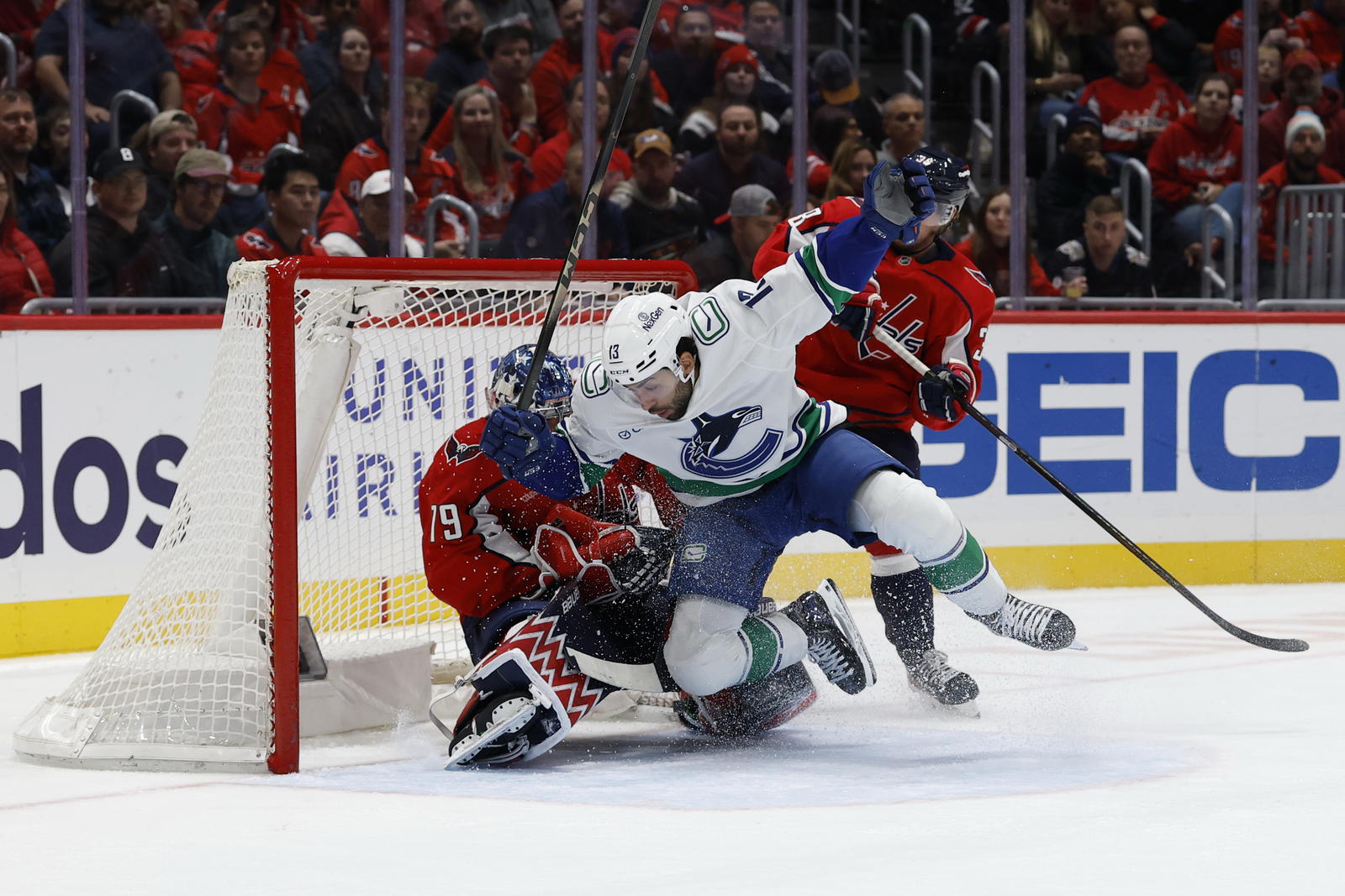 Oct 19, 2025; Washington, District of Columbia, USA; Vancouver Canucks left wing Arshdeep Bains (13) crashes into Washington Capitals goaltender Charlie Lindgren (79) during the second period at Capital One Arena. Mandatory Credit: Geoff Burke-Imagn Images
