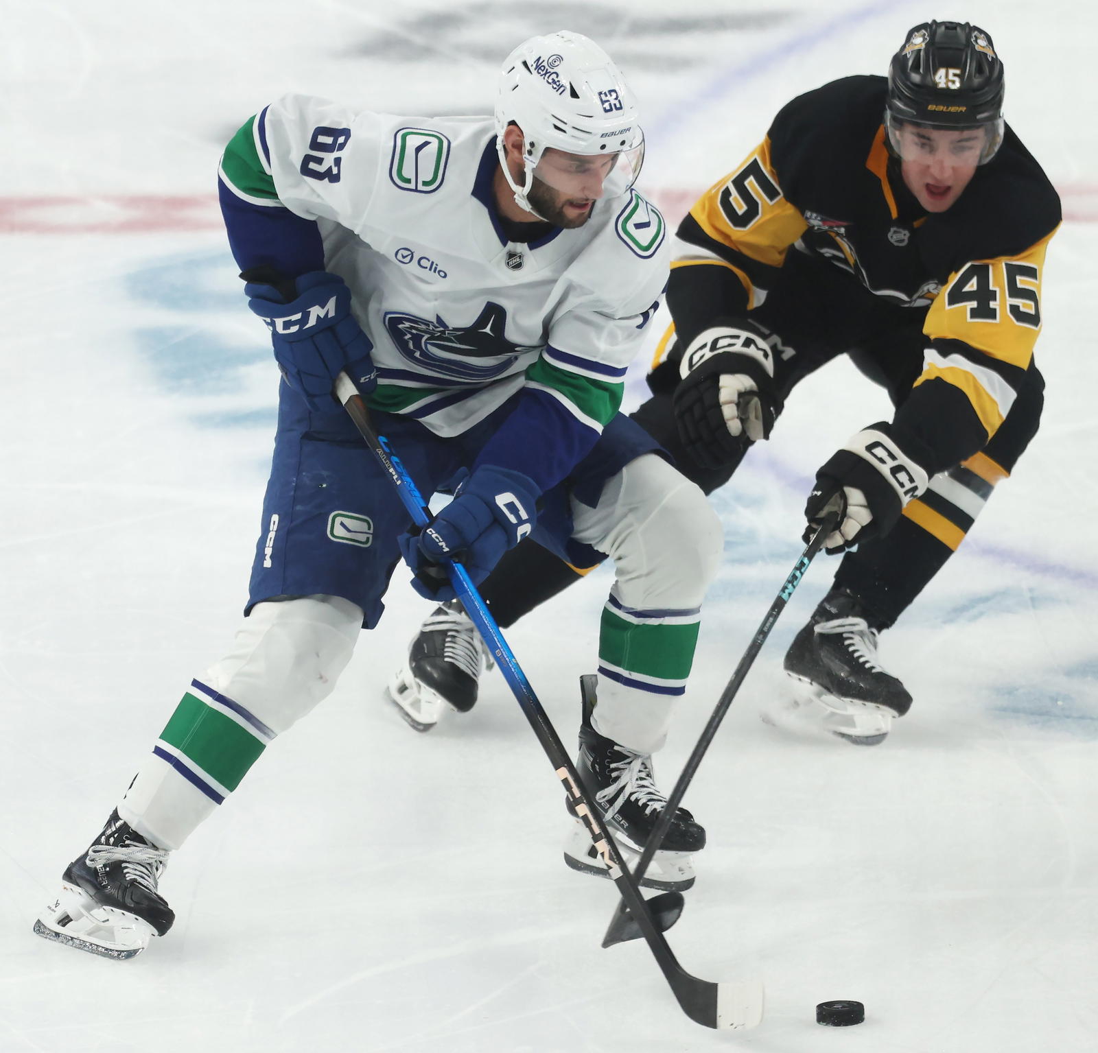 Oct 21, 2025; Pittsburgh, Pennsylvania, USA; Vancouver Canucks center Teddy Blueger (53) moves the puck against Pittsburgh Penguins defenseman Harrison Brunicke (45) during the second period at PPG Paints Arena. Mandatory Credit: Charles LeClaire-Imagn Images