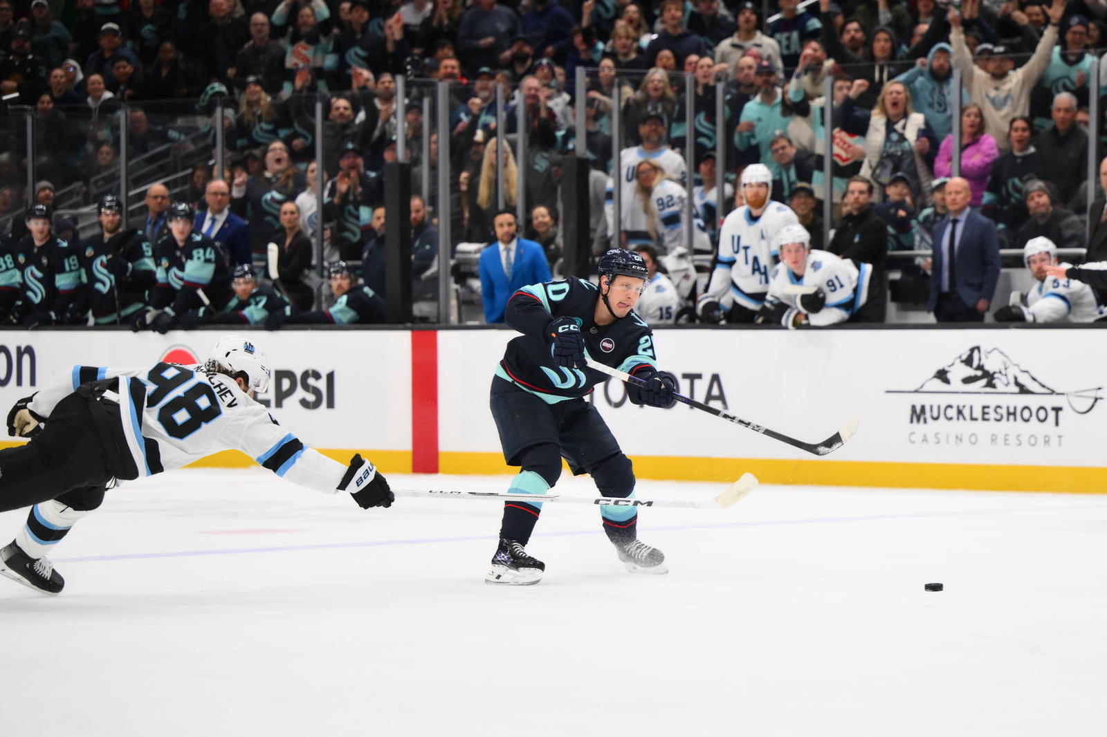 Mar 14, 2025; Seattle, Washington, USA; Seattle Kraken right wing Eeli Tolvanen (20) scores an empty net goal while defendd by Utah Hockey Club defenseman Mikhail Sergachev (98) during the third period at Climate Pledge Arena. Mandatory Credit: Steven Bisig-Imagn Images
