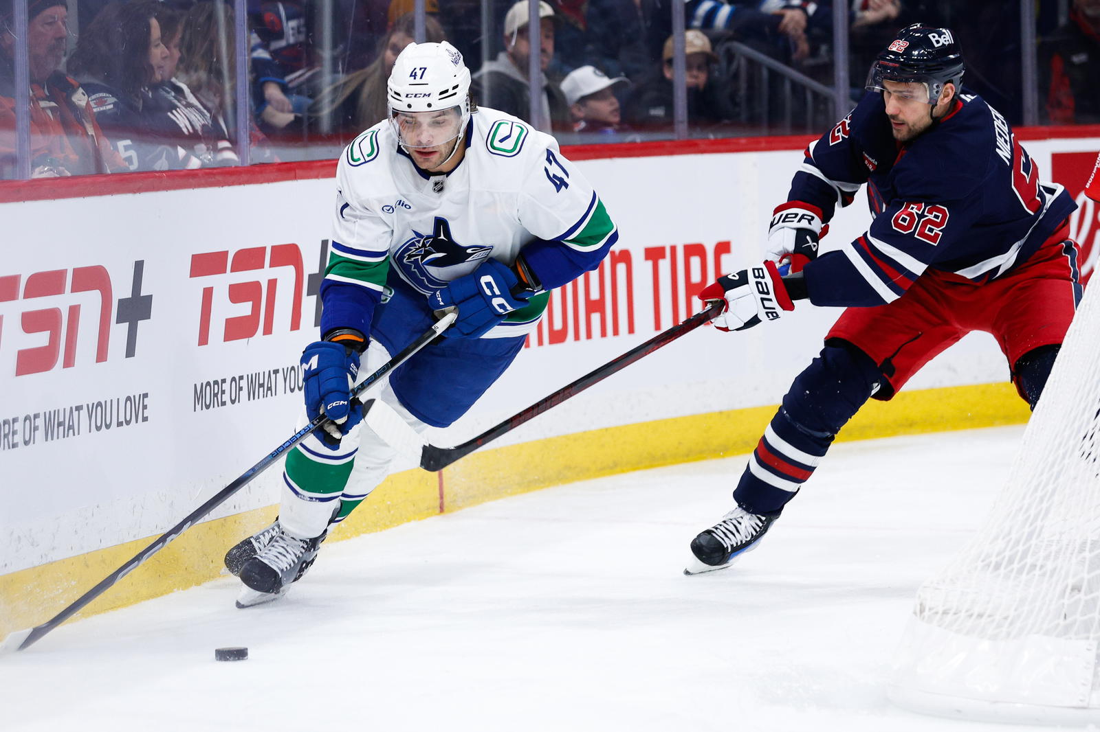 Jan 14, 2025; Winnipeg, Manitoba, CAN; Vancouver Canucks defenseman Noah Juulsen (47) tries to skate away from Winnipeg Jets forward Nino Niederreiter (62) during the second period at Canada Life Centre. Mandatory Credit: Terrence Lee-Imagn Images