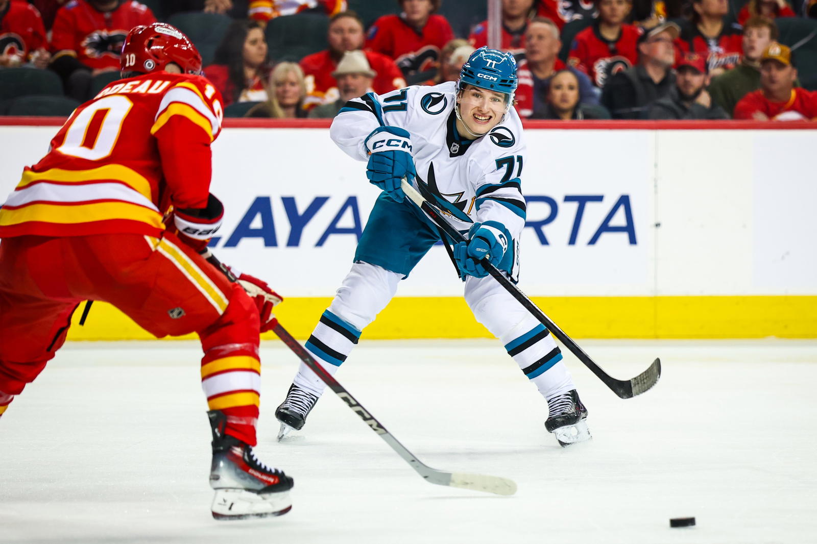 San Jose Sharks center Macklin Celebrini (71) passes the puck against Calgary Flames left wing Jonathan Huberdeau (10) during the third period at Scotiabank Saddledome. Mandatory Credit: Sergei Belski-Imagn Images