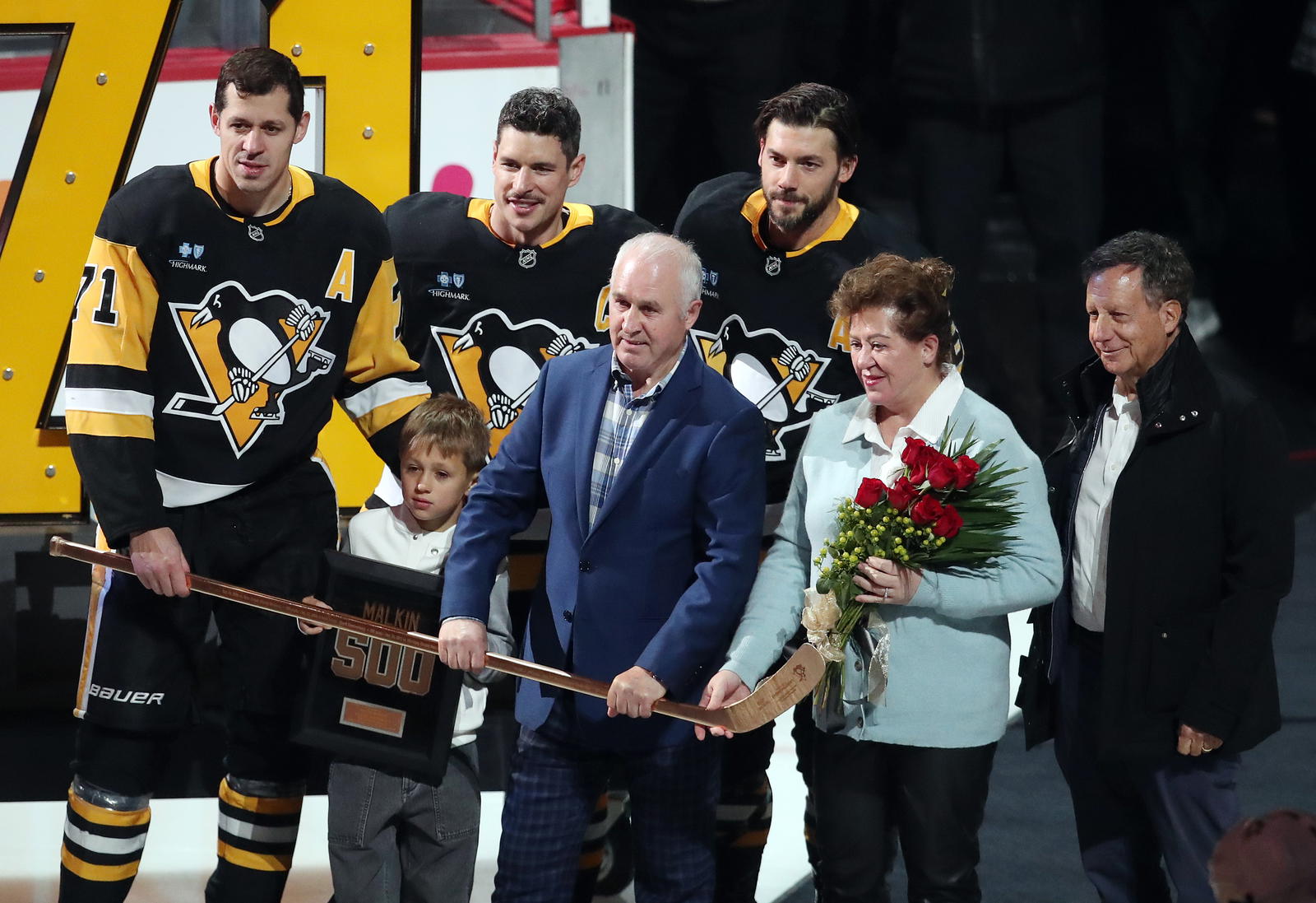 Nov 13, 2024; Pittsburgh, Pennsylvania, USA; Pittsburgh Penguins center Evgeni Malkin (71) is joined by teammates center Sidney Crosby (rear center), defenseman Kris Letang (rear right) along with son Nakita Malkin, father Vladimir Malkin, mother Natalia Malkin and Fenway Sports Group chairman Tom Werner (right) as he is honored for recording his 500th NHL goal earlier in the season before a game against the Detroit Red Wings at PPG Paints Arena. Mandatory Credit: Charles LeClaire-Imagn Images
