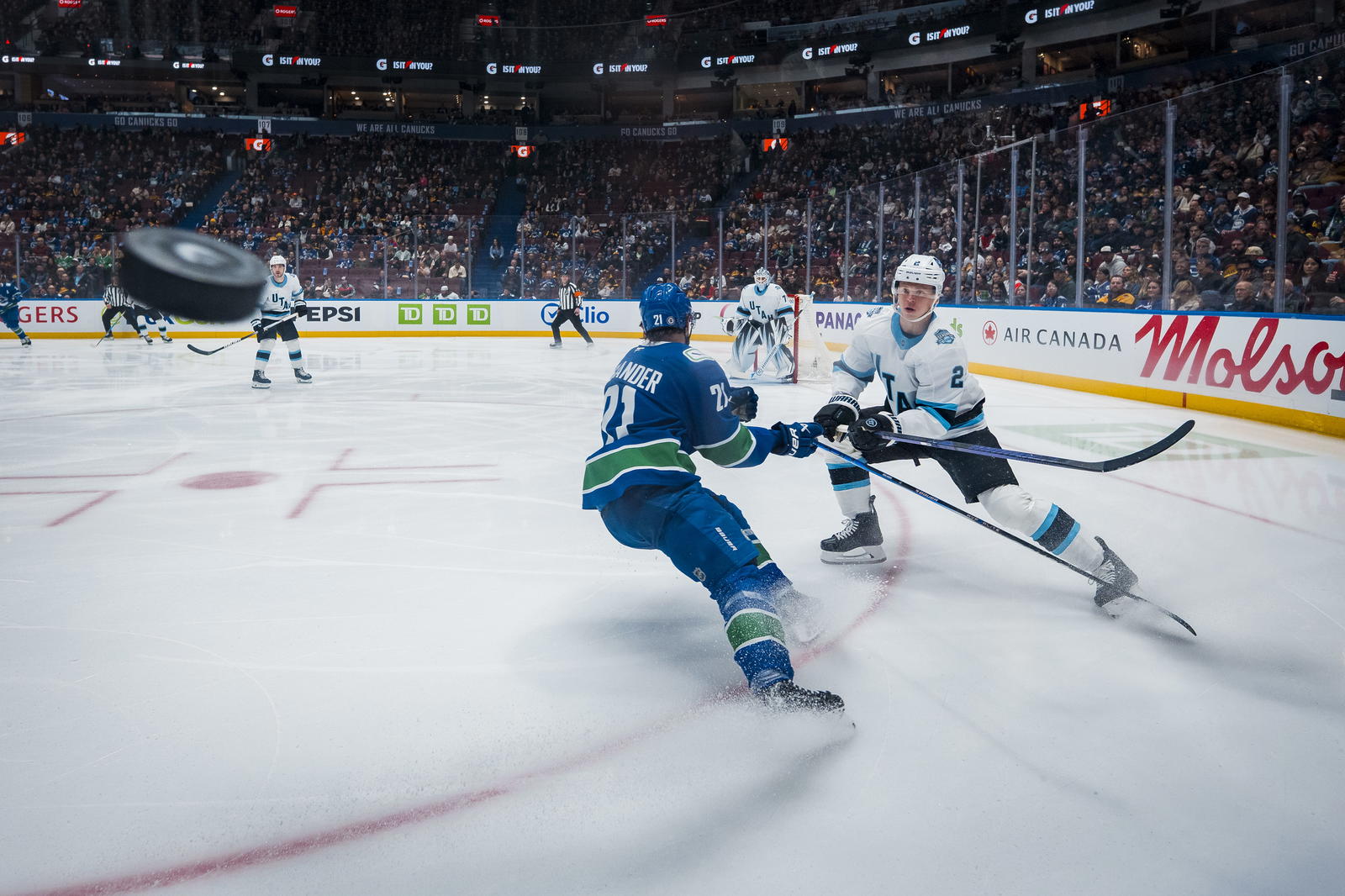 Mar 16, 2025; Vancouver, British Columbia, CAN; Utah Hockey Club defenseman Olli Maatta (2) shoots the puck past Vancouver Canucks forward Nils Hoglander (21) in the first period at Rogers Arena. Mandatory Credit: Bob Frid-Imagn Images