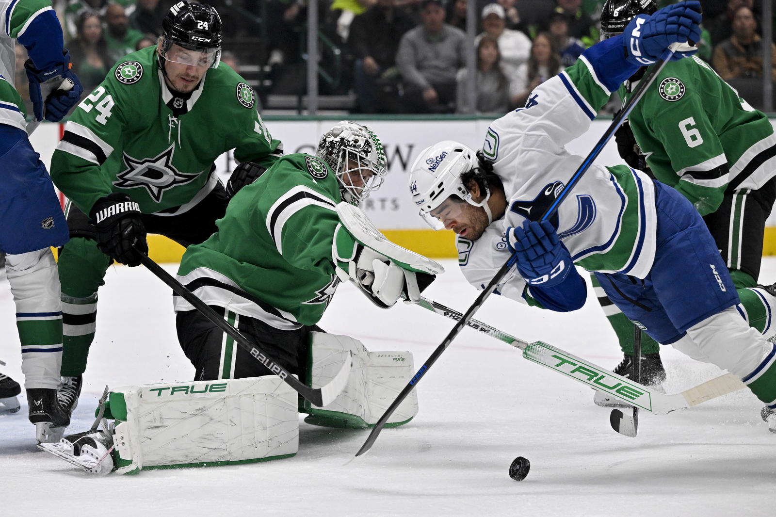 Apr 8, 2025; Dallas, Texas, USA; Vancouver Canucks left wing Kiefer Sherwood (44) attempts to poke the puck past Dallas Stars goaltender Casey DeSmith (1) during the first period at the American Airlines Center. Mandatory Credit: Jerome Miron-Imagn Images
