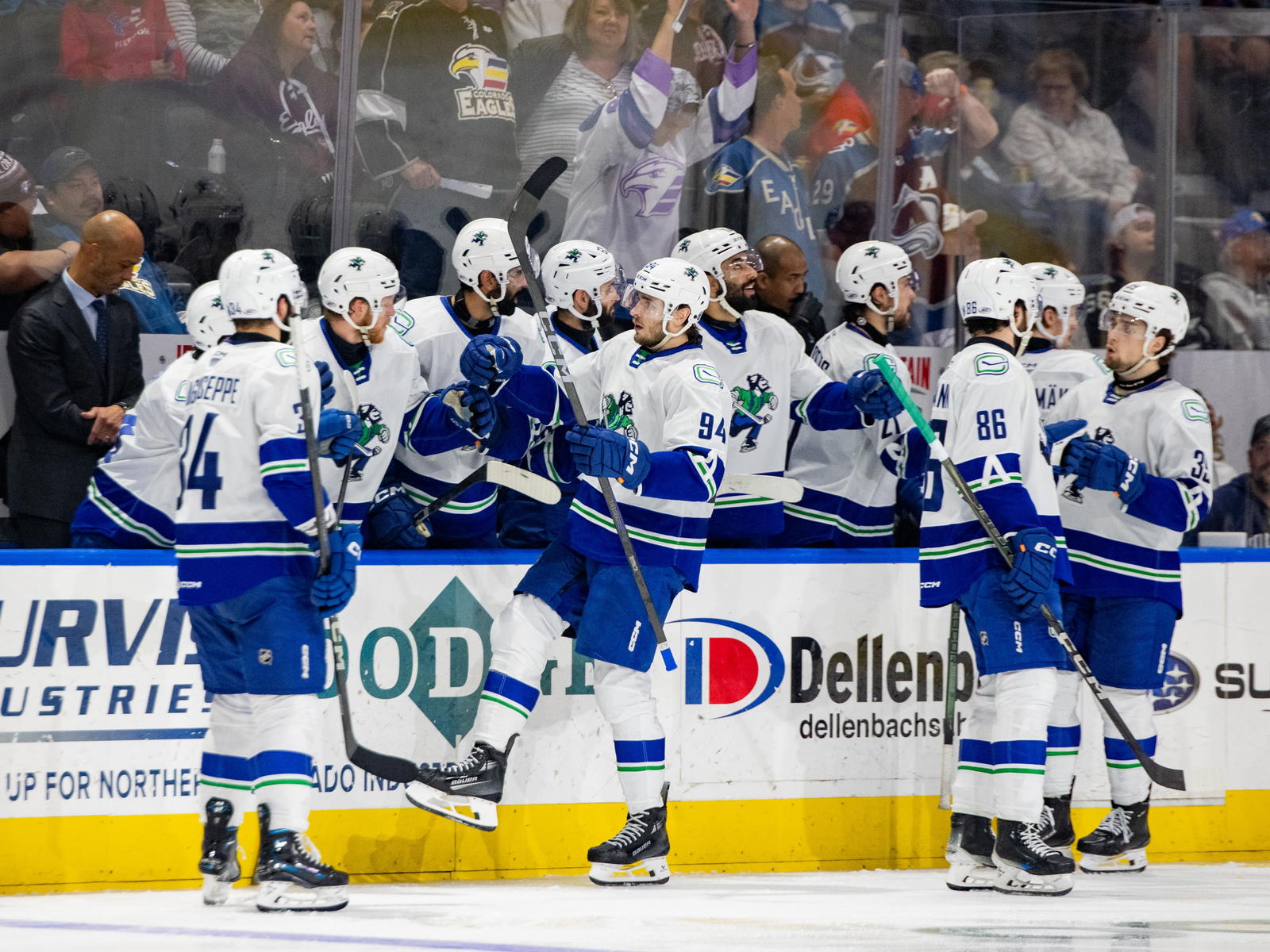 Abbotsford Canucks players Linus Karlsson (94), Phil Di Giuseppe (34), Christian Wolanin (86), and Ty Mueller (39) stand by the bench during a game. (Photo Credit: @AbbyCanucks/X)