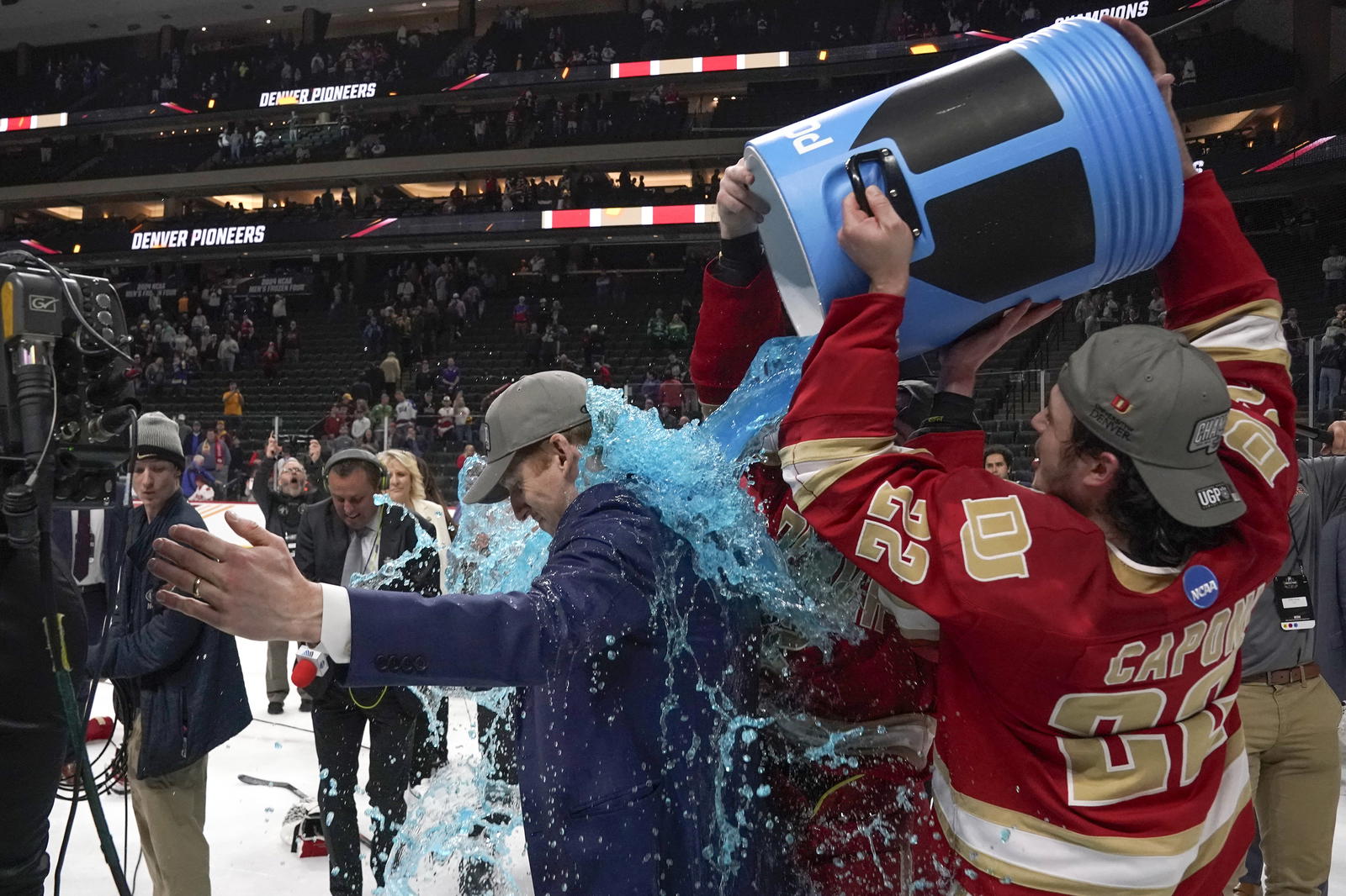 Apr 13, 2024; Saint Paul, Minnesota, USA; Denver Pioneers forward Connor Caponi (22) dumps blue Powerade on head coach David Carle after defeating the Boston College Eagles for the national championship at the 2024 Frozen Four college ice hockey tournament at Xcel Energy Center. (Credit: Nick Wosika-Imagn Images)