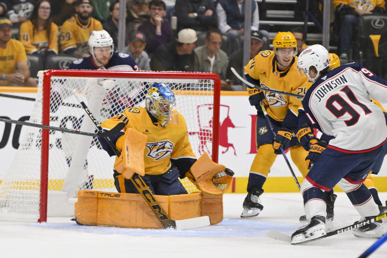 Oct 9, 2025; Nashville, Tennessee, USA; Nashville Predators goaltender Juuse Saros (74) blocks the shot of Columbus Blue Jackets center Kent Johnson (91) during the first period at Bridgestone Arena. Mandatory Credit: Steve Roberts-Imagn Images