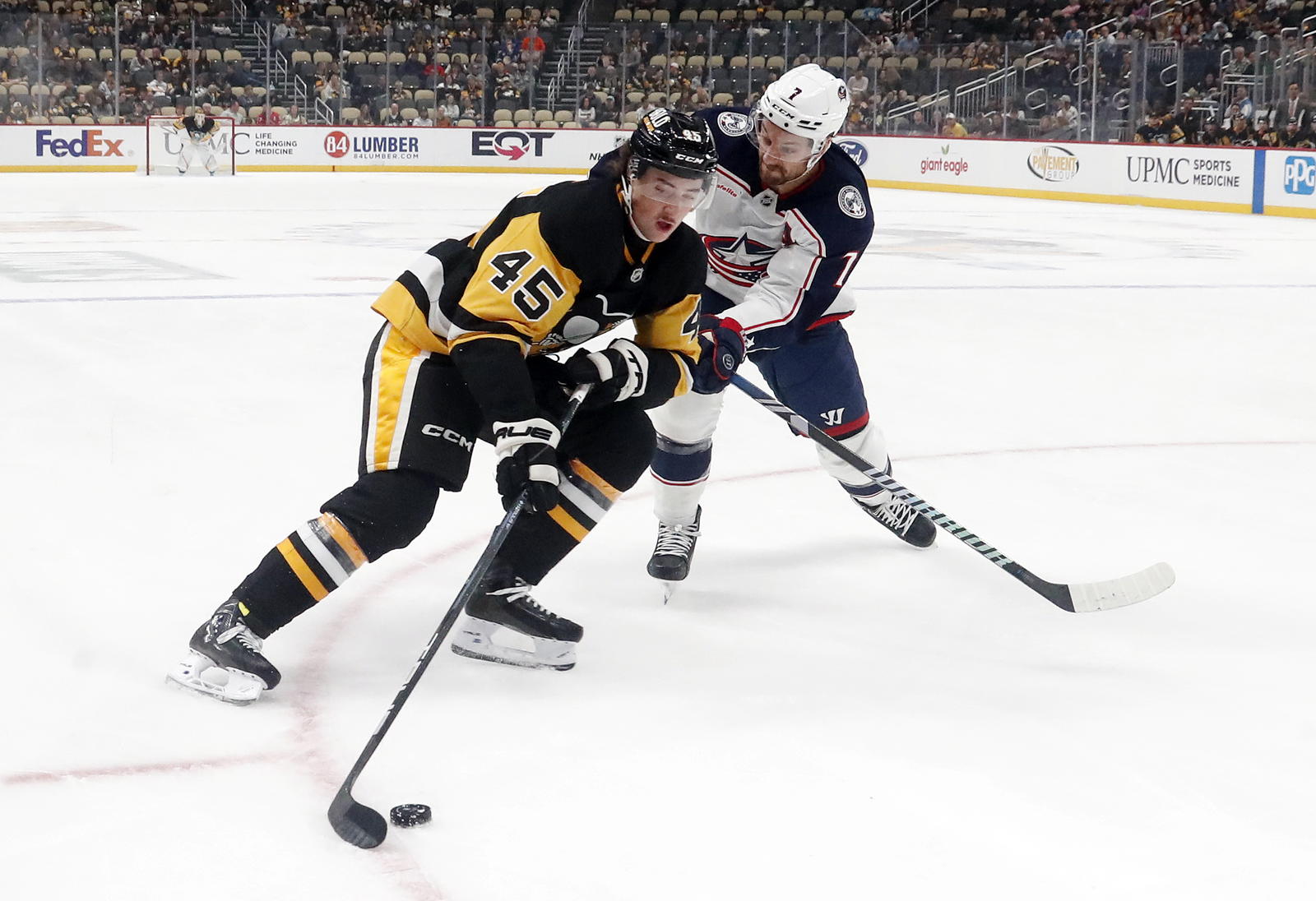 Oct 4, 2024; Pittsburgh, Pennsylvania, USA; Pittsburgh Penguins defenseman Harrison Brunicke (45) skates in on goal against Columbus Blue Jackets center Sean Kuraly (7) during the first period at PPG Paints Arena. Mandatory Credit: Charles LeClaire-Imagn Images