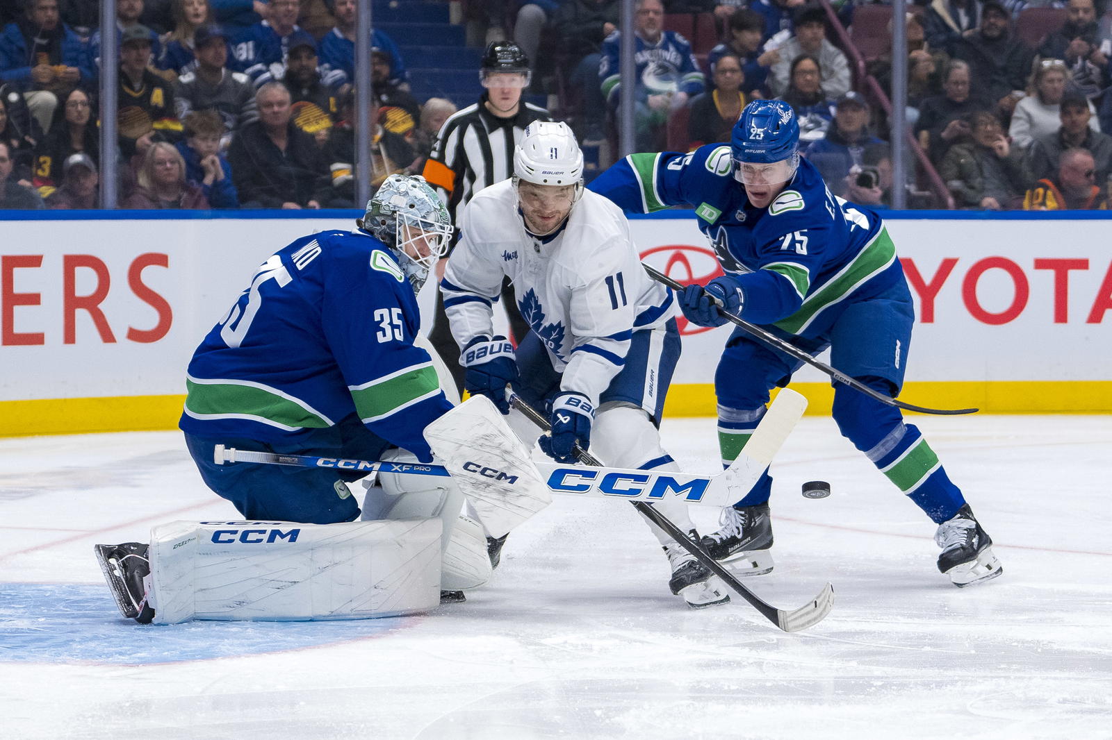 Feb 8, 2025; Vancouver, British Columbia, CAN; Vancouver Canucks defenseman Elias Pettersson (25) watches as goalie Thatcher Demko (35) makes a save on Toronto Maple Leafs forward Max Domi (11) in the first period at Rogers Arena. Mandatory Credit: Bob Frid-Imagn Images
