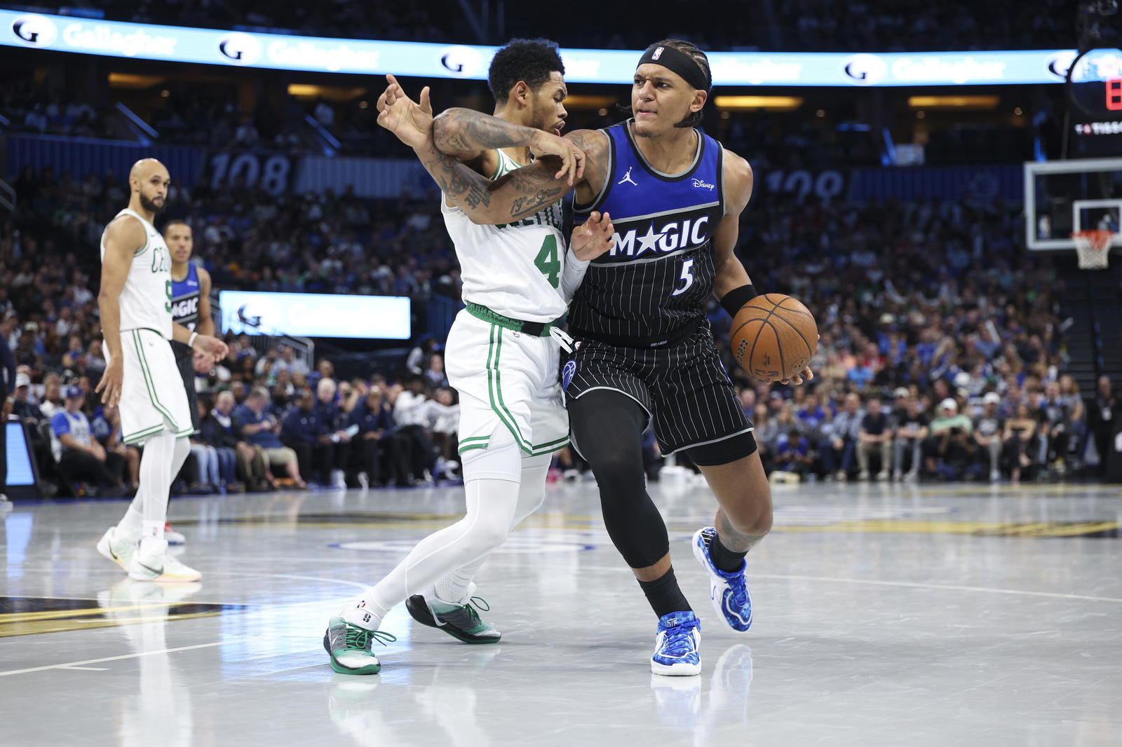 Nov 7, 2025; Orlando, Florida, USA; Orlando Magic forward Paolo Banchero (5) is guarded by Boston Celtics guard Anfernee Simons (4) in the fourth quarter at Kia Center. (Nathan Ray Seebeck/Imagn Images)