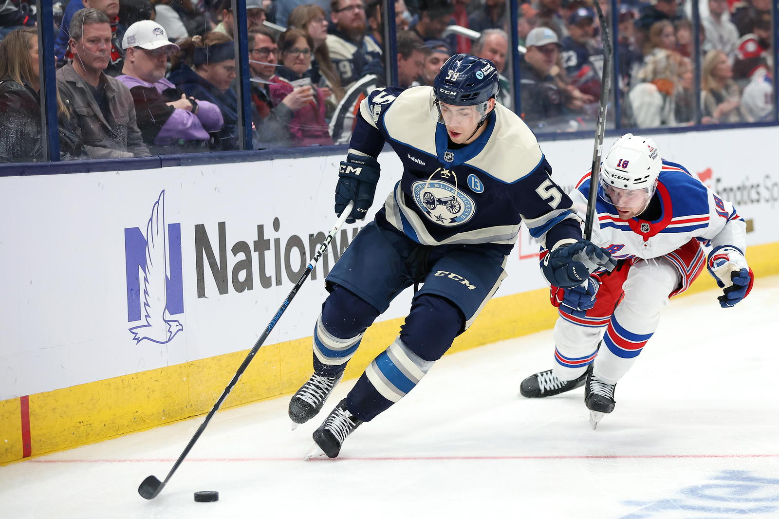 Mar 15, 2025; Columbus, Ohio, USA; Columbus Blue Jackets right wing Yegor Chinakhov (59) controls the puck as New York Rangers defenseman Urho Vaakanainen (18) defends during the second period at Nationwide Arena. Mandatory Credit: Joseph Maiorana-Imagn Images