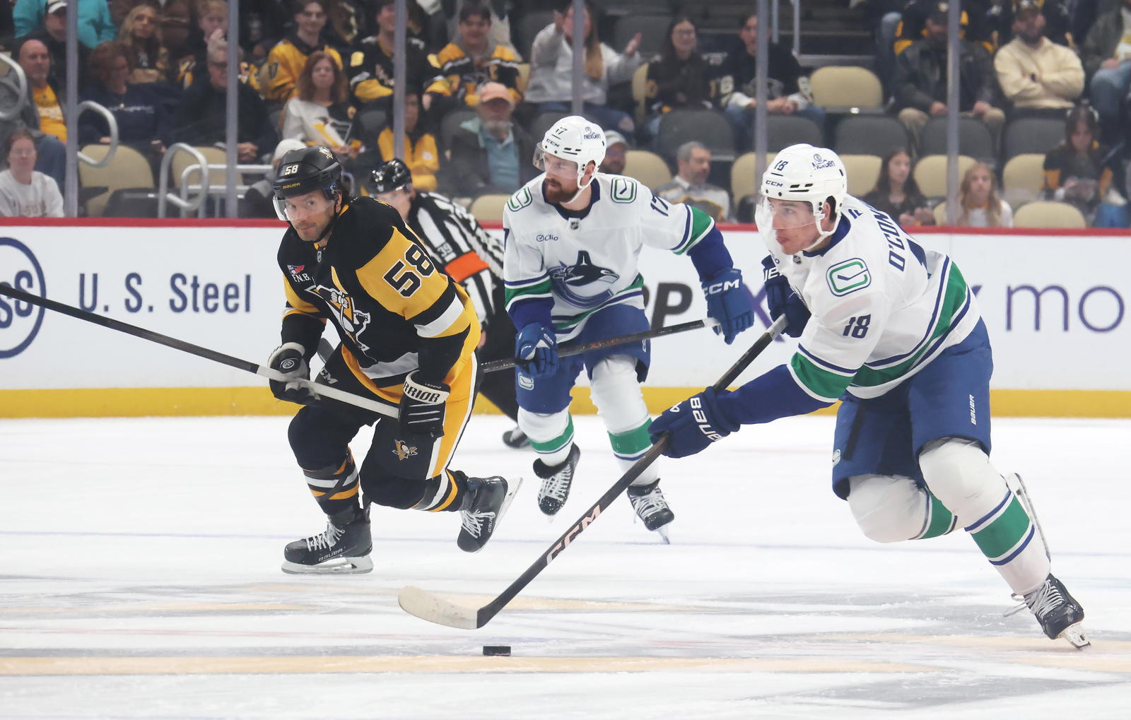 Oct 21, 2025; Pittsburgh, Pennsylvania, USA; Vancouver Canucks left wing Drew O'Connor (18) skates with the puck against the Pittsburgh Penguins during the first period at PPG Paints Arena. Mandatory Credit: Charles LeClaire-Imagn Images