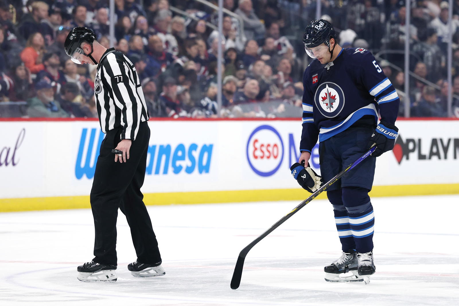 Mar 30, 2025; Winnipeg, Manitoba, CAN; Winnipeg Jets defenseman Luke Schenn (5) and linesman Caleb Apperson (77) check out some bad centre ice during a game against the Vancouver Canucks in the second period at Canada Life Centre. (James Carey Lauder-Imagn Images)