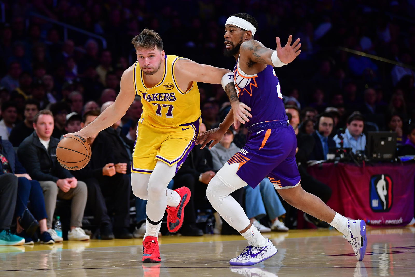 Los Angeles Lakers guard Luka Doncic (77) moves the ball against Phoenix Suns guard Jordan Goodwin (23) during the second half at Crypto.com Arena.&nbsp;Gary A. Vasquez-Imagn Images