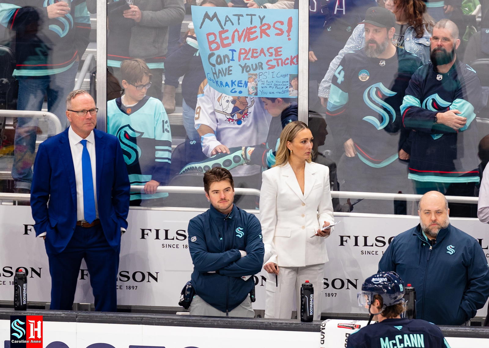 Assistant Coach Jessica Campbell (in white suit) behind the Kraken bench at Climate Pledge Arena. Photo by Caroline Anne