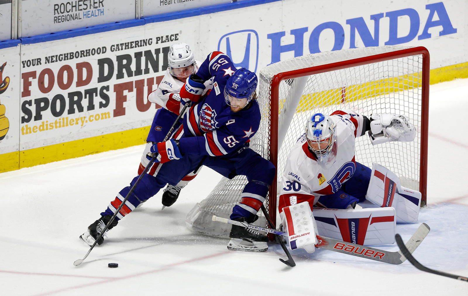 Rochester’s Josh Dunne tries to carry the puck around the net against Laval’s Gustav Linstrom and goalie Cayden Primeau. Photo credit:&nbsp;Jamie Germano/Rochester Democrat and Chronicle / USA TODAY NETWORK via Imagn Images