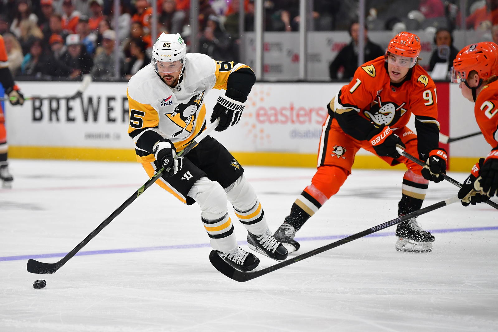 Oct 14, 2025; Anaheim, California, USA; Pittsburgh Penguins defenseman Erik Karlsson (65) moves the puck against Anaheim Ducks center Leo Carlsson (91) during the first period at Honda Center. Mandatory Credit: Gary A. Vasquez-Imagn Images
