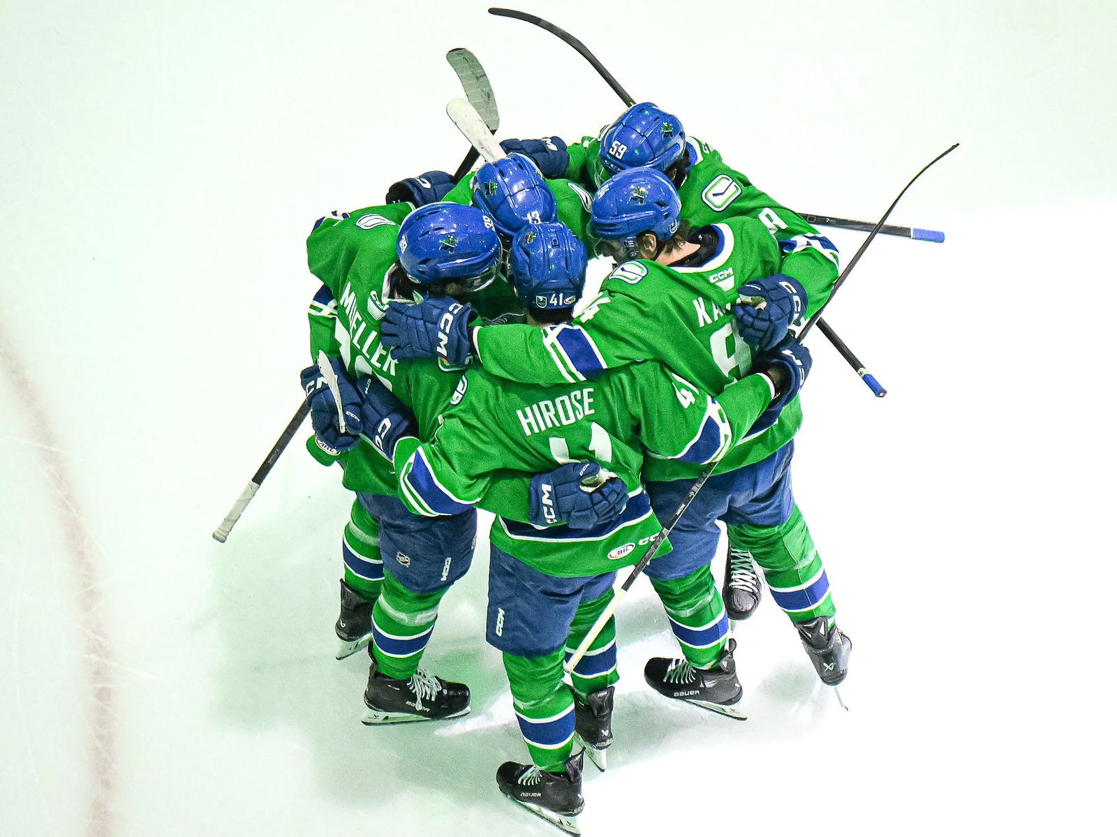 Abbotsford Canucks players Ty Mueller (39), Akito Hirose (41), Linus Karlsson (94), Kirill Kudryavstev (59), and Arshdeep Bains (13) huddle together on the ice. (Photo Credit: @AbbyCanucks/X)&nbsp;