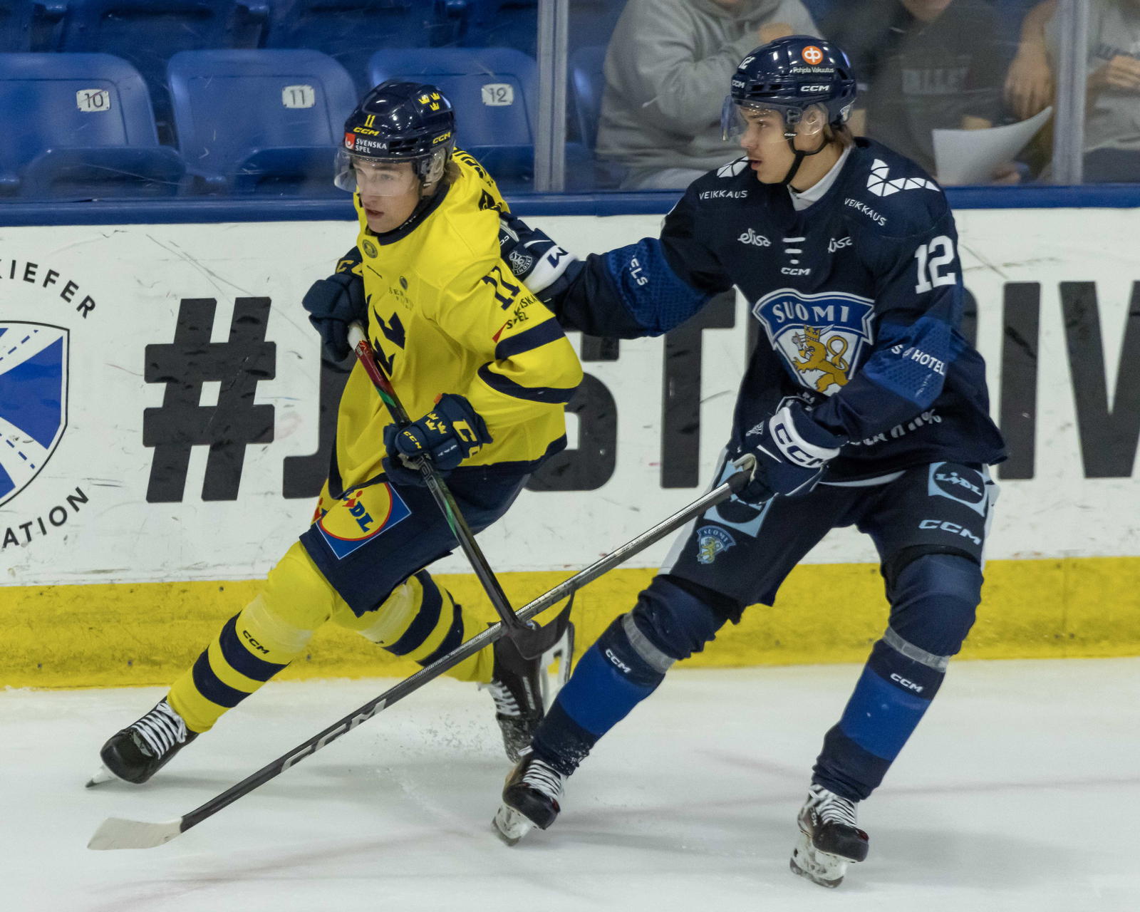 Aug 3, 2024; Plymouth, MI, USA; Finland's forward Sebastian Soini (12) defends against Sweden's forward Lucas Pettersson (11) during the first period of the 2024 World Junior Summer Showcase at USA Hockey Arena. Mandatory Credit: David Reginek-Imagn Images