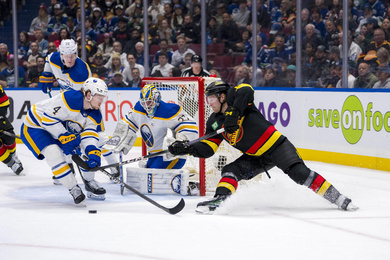 Mar 19, 2024; Vancouver, British Columbia, CAN; Buffalo Sabres goalie Devon Levi (27) watches as defenseman Bowen Byram (4) stick checks Vancouver Canucks forward Brock Boeser (6) in the first period at Rogers Arena. Mandatory Credit: Bob Frid-Imagn Images