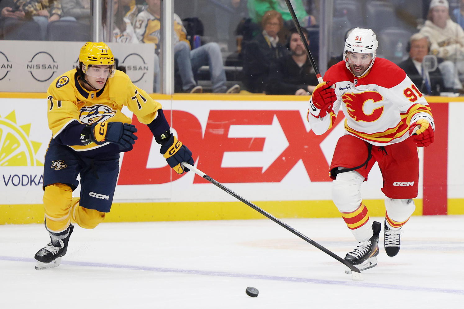 Nov 1, 2025; Nashville, Tennessee, USA; Nashville Predators right wing Matthew Wood (71) and Calgary Flames center Nazem Kadri (91) chase after the puck during the third period at Bridgestone Arena. Alan Poizner-Imagn Images