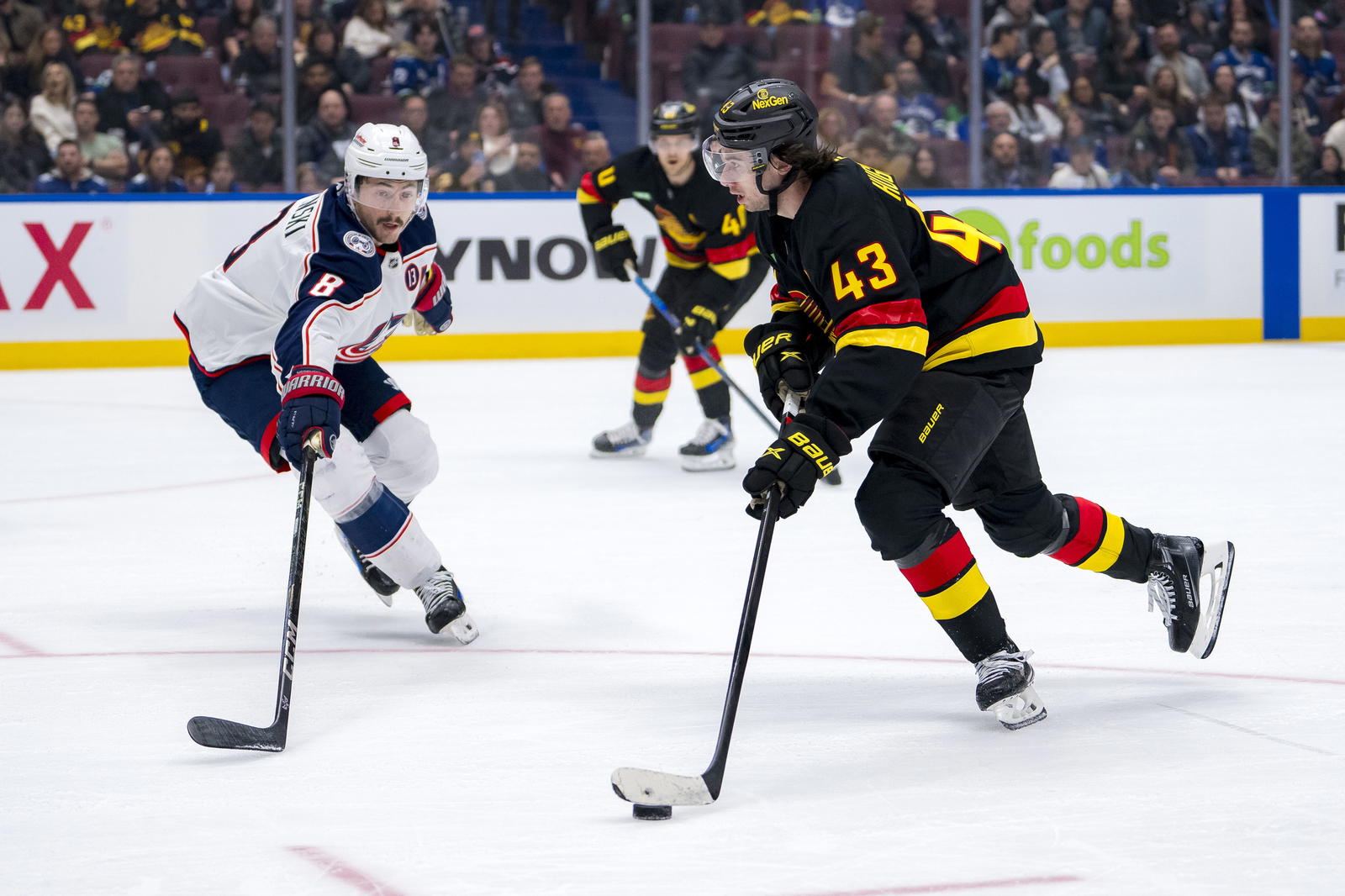 Quinn Hughes skates past Zach Werenski. (Bob Frid-Imagn Images)